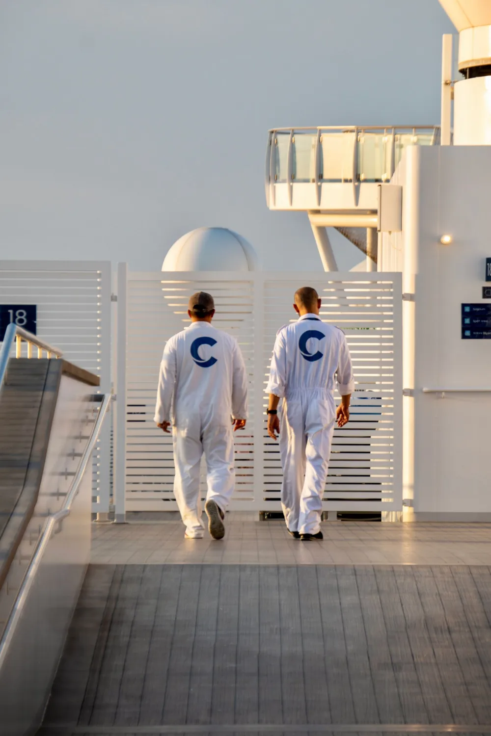 Uniformed crew members walking on the deck of a passenger vessel